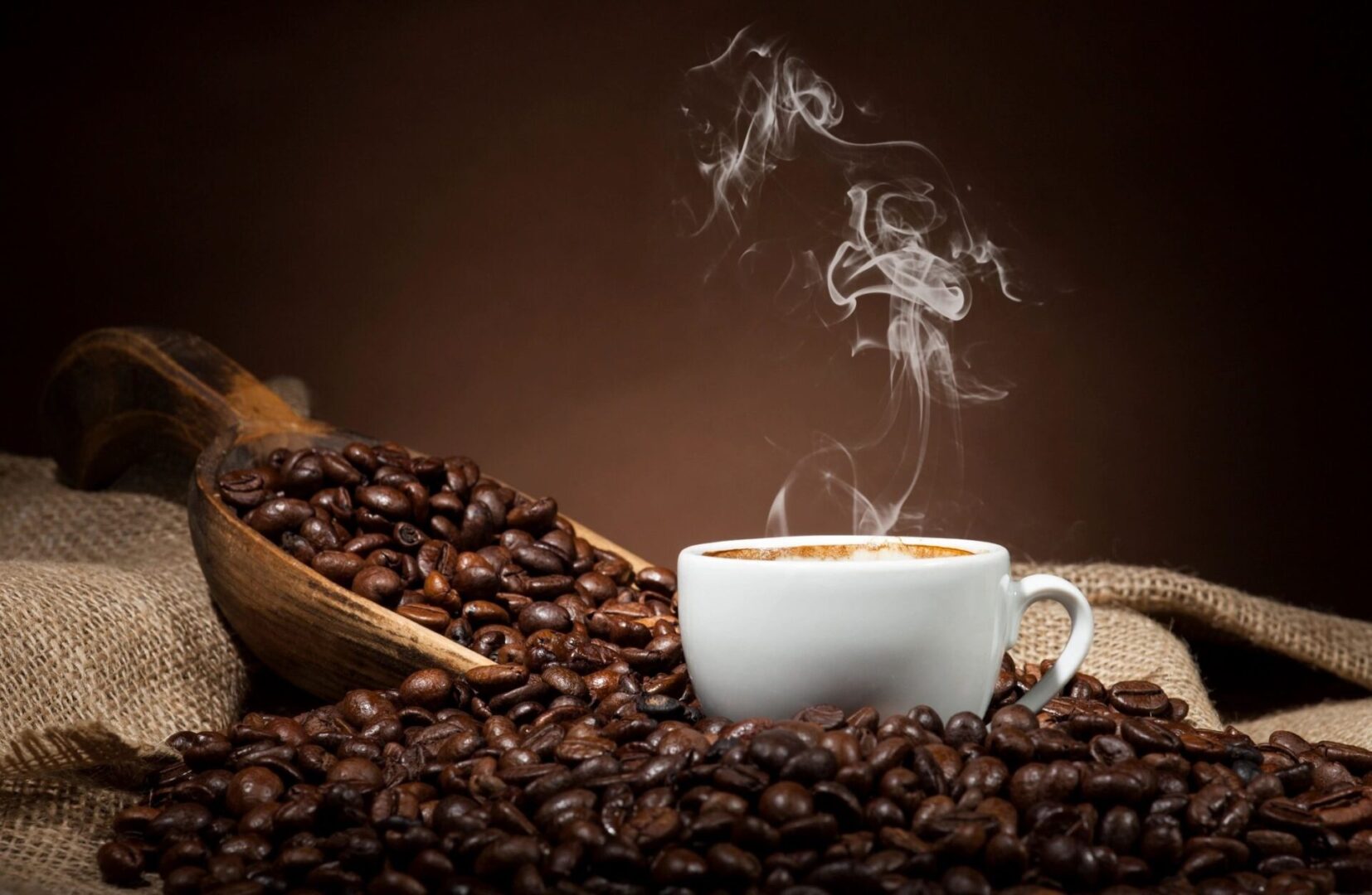 White cup with coffee beans on dark background